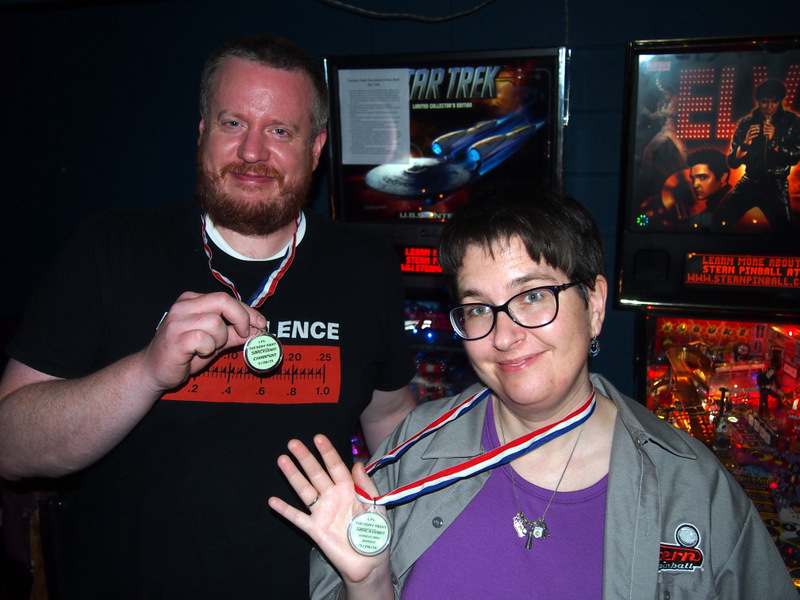 Mike and Heather holding up their medals in front of Star Trek.