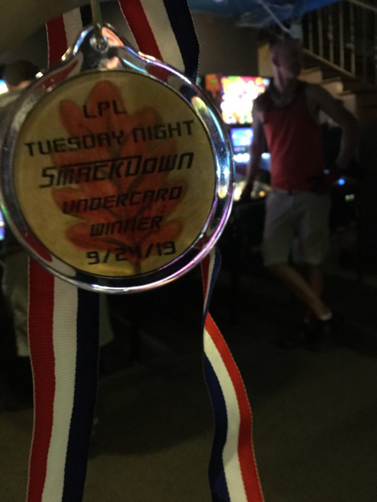 A medal with a fall leaf held up, and a player out of focus in the background.