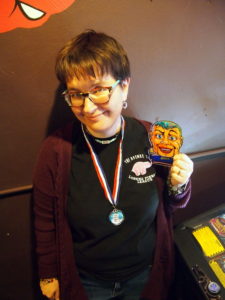 Heather wearing a medal and holding up a plastic cutout of Rudy from FunHouse.