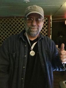 Pat facing forward, smiling and wearing a medal.