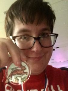 A closeup self-portrait of Heather holding her medal in front of her face.